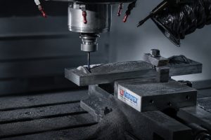 Maquinado CNC de una pieza de grafito industrial durante el proceso de fabricación sobre plano.